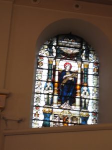 The south window represents the figure of Ruth and the north Rebecca, the name she took at her baptism. Both incorporate cartouches of Pocahontas, also depicted are her baptism in one and Ruth accompanying Naomi in the other. Within the borders one sees American plants: Virginia creeper, dogwood saragas and redbud